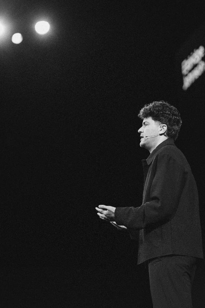 A speaker presenting under the stage lights