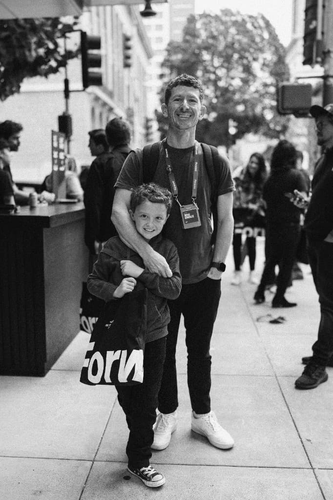An attendee and his son outside the venue with a Forward tote bag
